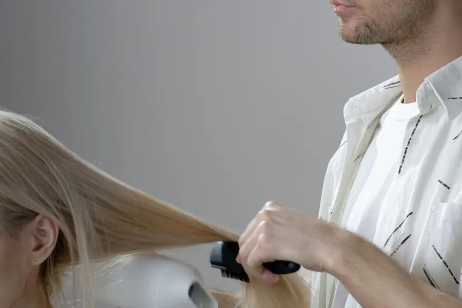 De klant van 15:30 in de stoel, de kapper föhnt haar haar
