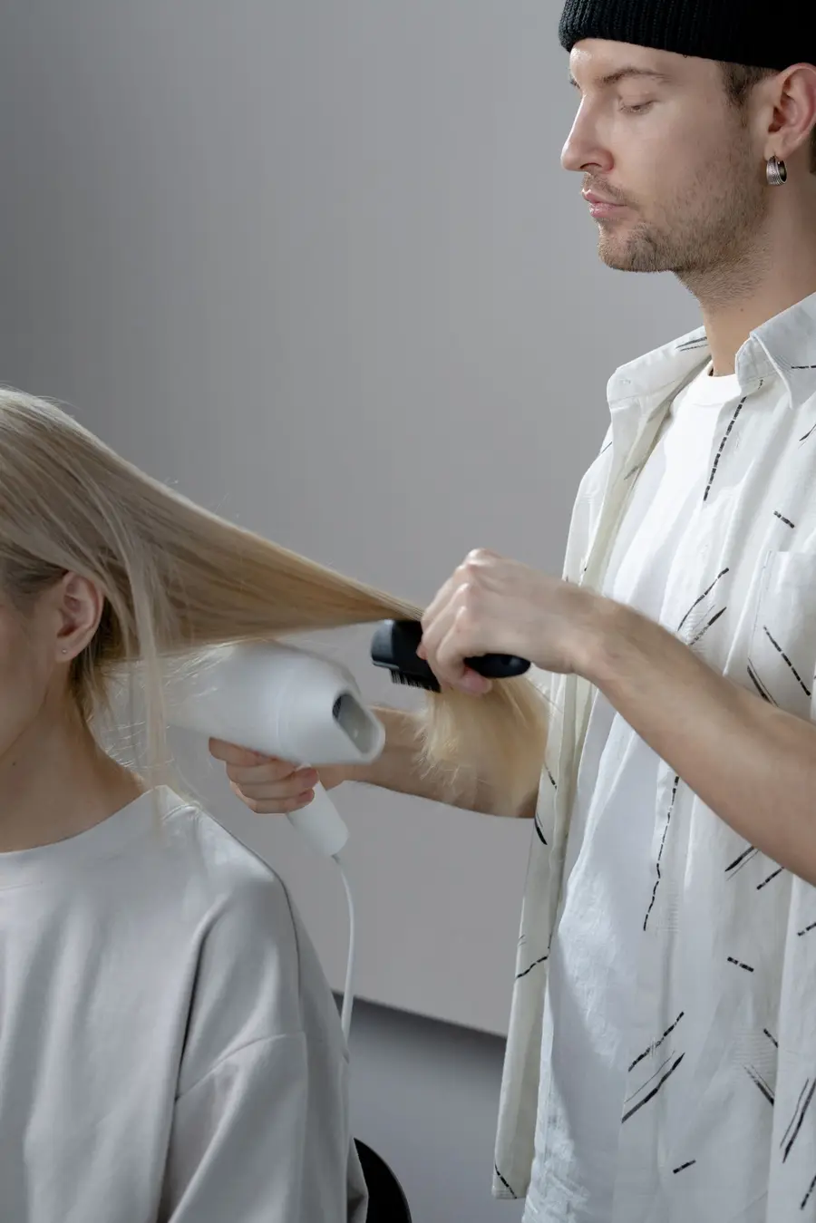 Een kapper föhnt het haar van een klant