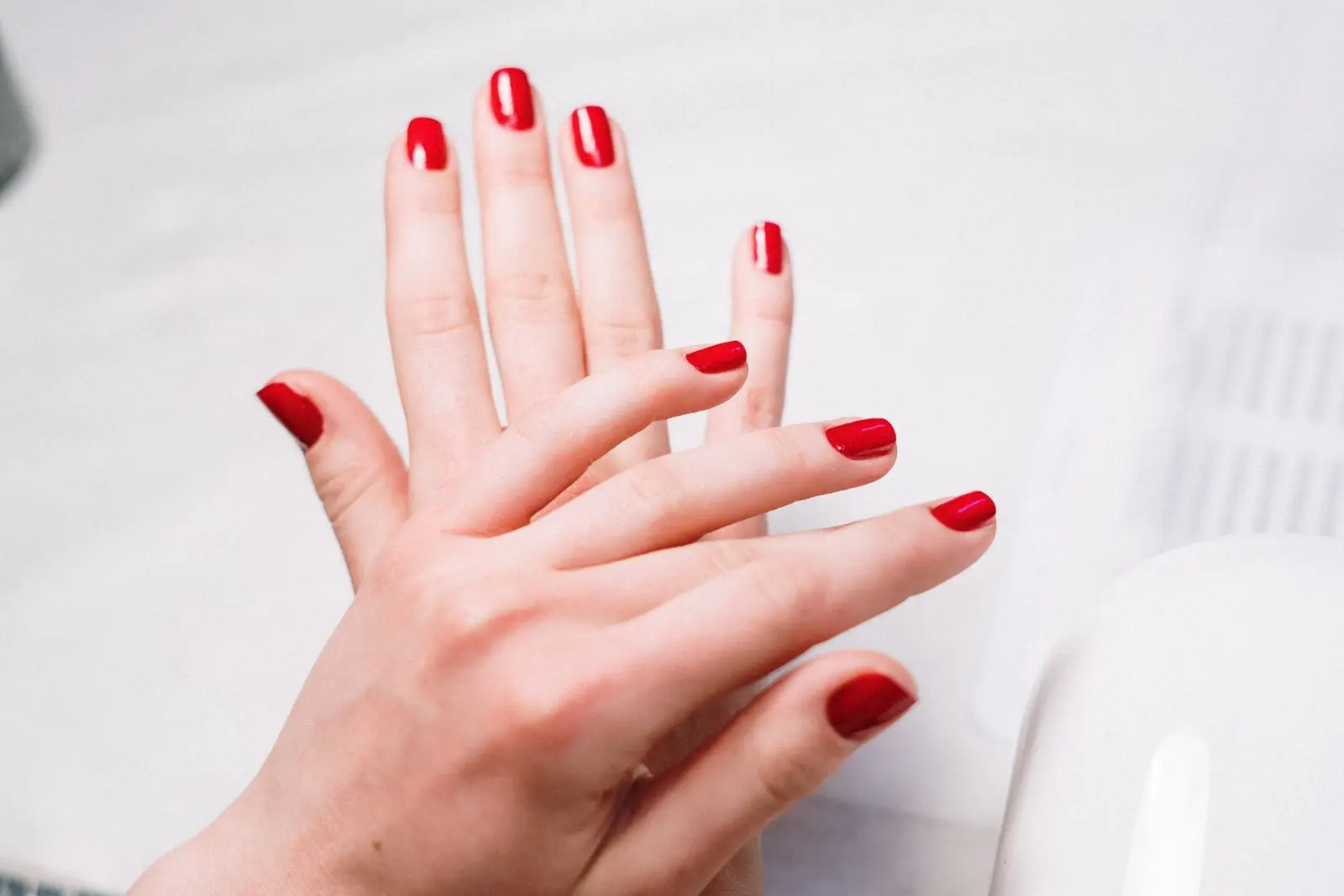 Twee handen met pas gelakte rode nagels